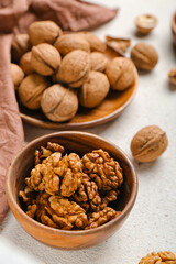 Bowl of fresh walnut kernels on light background, closeup