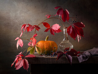 Still life with a pumpkin and a branch of wild grapes