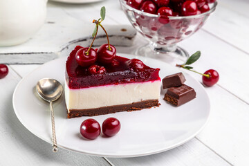 A piece of cherry cheesecake on a plate on a white table