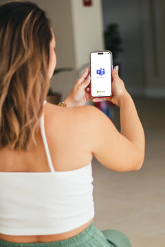 Girl in the hotel lobby holding a smartphone iPhone 14 Pro with Microsoft Teams app on the screen. Sunny day. Rio de Janeiro, RJ, Brazil. October 2022