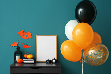 Chest of drawers with frame, Halloween pumpkins and balloons near color wall