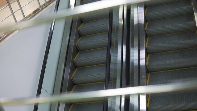 Metallic escalator, moving stairs in a mall. Dutch angle elevating climber in an airport.