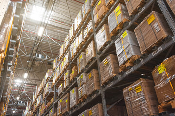 Retail warehouse full of shelves with goods in wooden crates, boxes and packages. Logistics, sorting and distribution for product delivery. Look up, light.