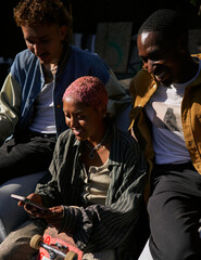 Four young friends in backyard hanging out on phone