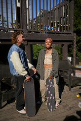 Two young non-binary skateboarders in backyard hanging out with skateboards
