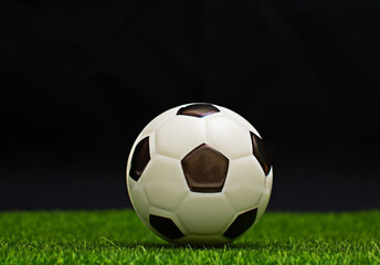 soccer ball placed on green grass on black background