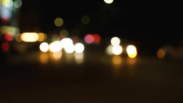 Defocused car lights on a night city street. Abstraction. Blurred background. Multicolored circles of light. Slow motion