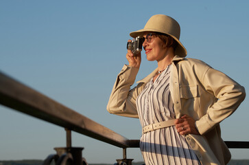 Obraz premium Woman tourist in a straw hat takes pictures on the street with a vintage camera