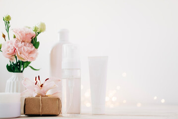 Fototapeta na wymiar Beauty products bottles with present box and flowers. Holiday gift cosmetic concept