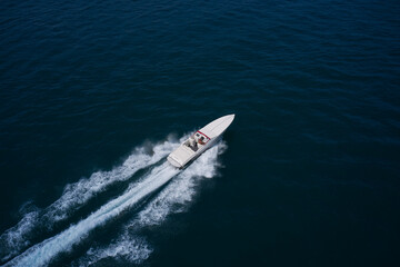 a man in a red hat on a speedboat fast movement on the water. White super speed big boat moves fast on dark water air view.