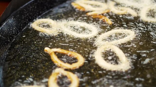 Delicious churros being cooked in hot oil. Also known as fried doughs.