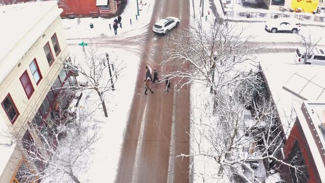 Aerial view of people crossing the street in a snow filled winter wonderland.