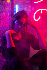 Obraz na płótnie Canvas Caucasian woman in sunglasses posing in fog in neon studio.