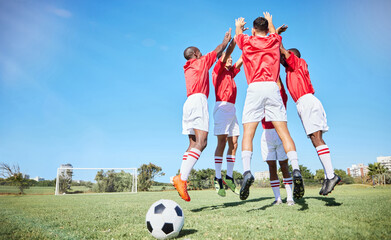 Soccer, sports and motivation with a team jumping on a grass pitch or field during training or...