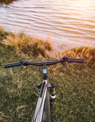 Naklejka premium Mountain bike on a lake shore. Summer sunset adventures in the countryside. Using a bicycle in rural area.