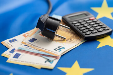 Electric plug and euro money on european union flag. Concept of energy crisis.