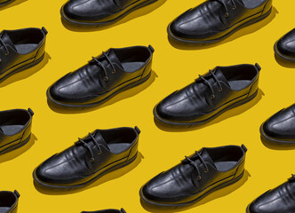 Shoe pattern. Black shoes on a yellow background top view with shadow. Accessories concept. New leather shoes. Classic office style. Men's fashion shoe. Flat minimalistic store advertising. Footwear