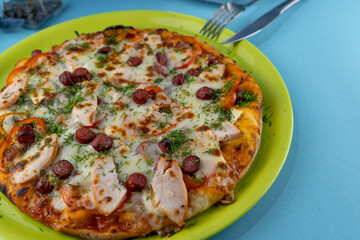 Pizza with meat, bacon, sausages, sausage, parmesan and dill, cheese, sauce. Food in a plate on a blue background. Menu. Homemade pastries. Meal with meat. Food on the table.