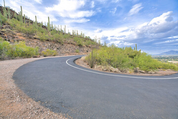 U-shaped concrete bike path and walkin pathway near a slope with saguaro cactuses at Tucson, AZ