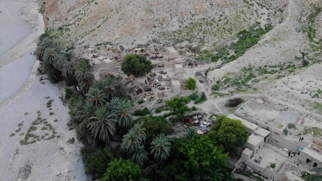 Aerial View Of Village Located In Khuzdar With Green Trees And Gardens Surrounded By Desert Landscape