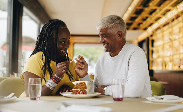 Happy senior couple sharing a delicious cake in a cafe