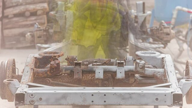 Close up shot of man in a protective clothing and hard hat processes metal with a stream of sand. Worker in sandblasting uniform
