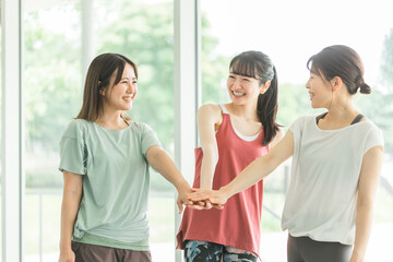 スポーツジムで仲間と円陣を組むスポーツウェアのアジア人の女性達
