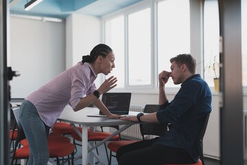 Emotional couple of young colleagues arguing in modern office. African-american business woman shouting at her sad man assistant, copy space, side view