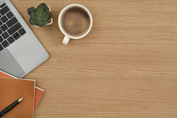 Flat lay, cup of coffee, laptop computer, notebook and succulent plant on wooden office desk. Top view with copy space