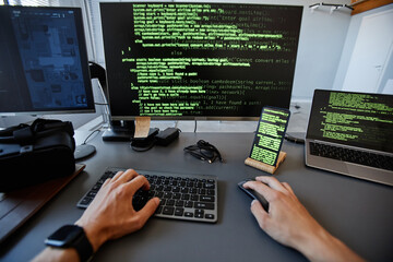 POV shot of computer programmer working with green code lines on multiple device screens, copy space