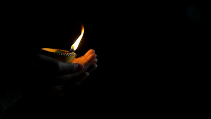 Indian Festival Diwali. Indian girl holding diya for Diwali. girl holding lit diya lamp in hands, closeup. Diwali celebration