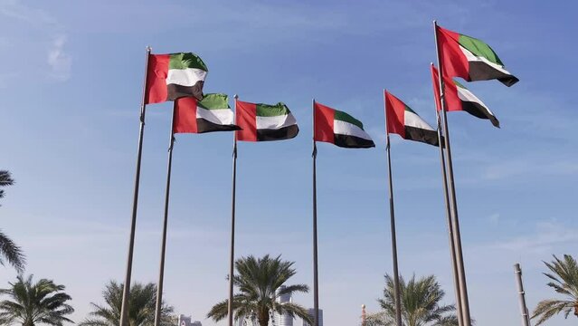 National symbol of United Arab Emirates flags in blue sky background. Seven UAE flags represent seven emirates  waving in wind. 