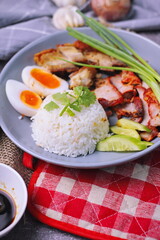 rice with red pork on top served with boiled egg, cucumber and crispy pork with dipping sauce and soy sauce served in the restaurant