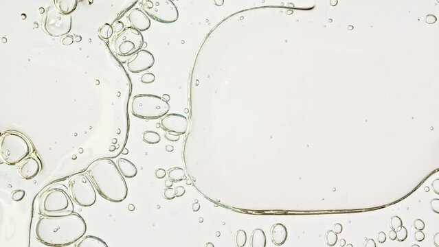 Transparent cosmetic gel fluid with molecule bubbles oil distribution on a white background. Macro Shot of Natural Organic Cosmetics, Medicine. Production Close-up. Slow Motion. High quality 4k