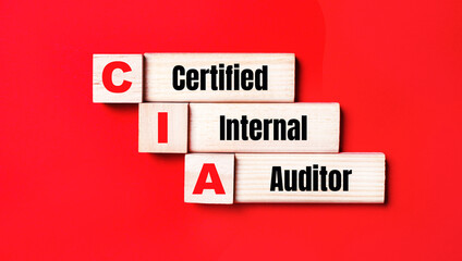 On a bright red background, wooden cubes and blocks with the text CIA Certified Internal Auditor. Manufacturing of wooden toys.