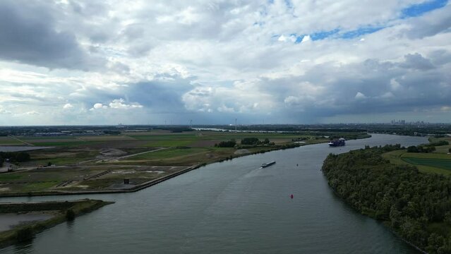 Bird eye view of BG Onyx, a freight line container ship sailing across river of Zwijndrecht with dramatic sky and vast landscapes