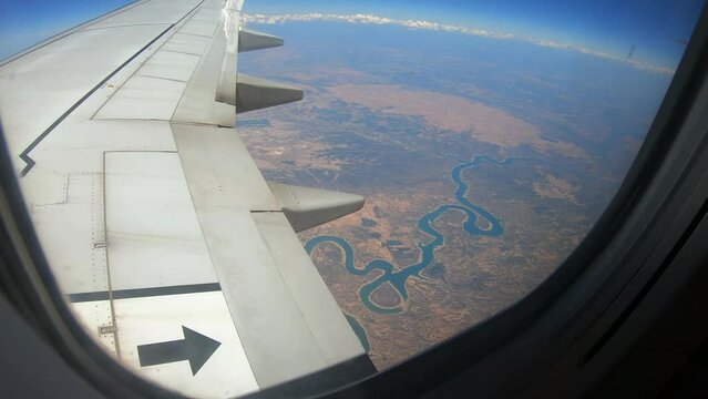 silohuette of a blue river from the window of an airplane flying over spain on a sunny day