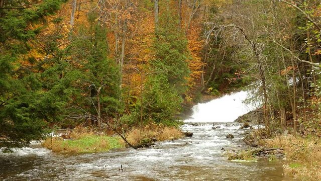 Beautiful waterfall at a autumn forest in Canada. Ice melting sustainable water concept. Scenic static wide shot