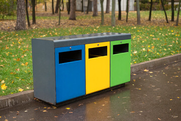 Three different garbage container for sorting waste in the park. Yellow for plastic, green for...