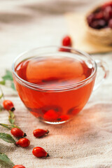 A cup of rose hip tea with fresh berries in a glass cup. Vintage background, selective focus