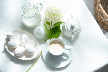 White still life in a high key with milk, eggs and a cup of cappuccino.