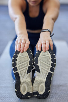 Woman runner stretching, sports shoes and athlete touching toes on a yoga mat on floor for leg fitness warm up exercise. Female athlete, training for flexibility and healthy cardio running workout