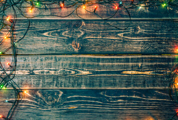 Christmas background made of dark wooden boards with a garland and a place to copy.
