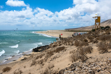 View of beach in Fuerteventura island with windsurfers in blue turquoise water during summer vacation holidays