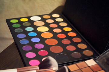 Photo of multi-colored makeup stylist's palette and bones in the foreground in defocus