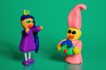 A toy girl and a dwarf with a gift on a green background.