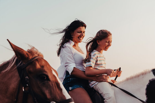 Mother and daughter enjoy riding horses together by the sea. Selective focus 