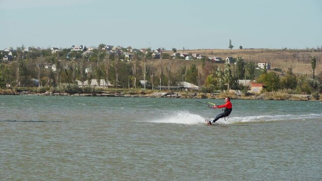 Kiteboarder rides on a kite in sea bay. Freestyle kiter training on pond kiteboarding spot. Kitesurfer enjoying ride. Extreme water sports. Slow motion 120 fps.