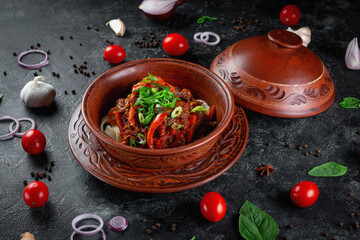 Traditional Kazakh dish Kuirdak. Aromatic roast of by-products, lamb meat with lots of onions and vegetables in a clay pot
