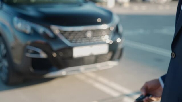 Young businessman in suit picks up a car at the dealership, dealer hands over the keys to a new car to the owner, rental car for a trip.